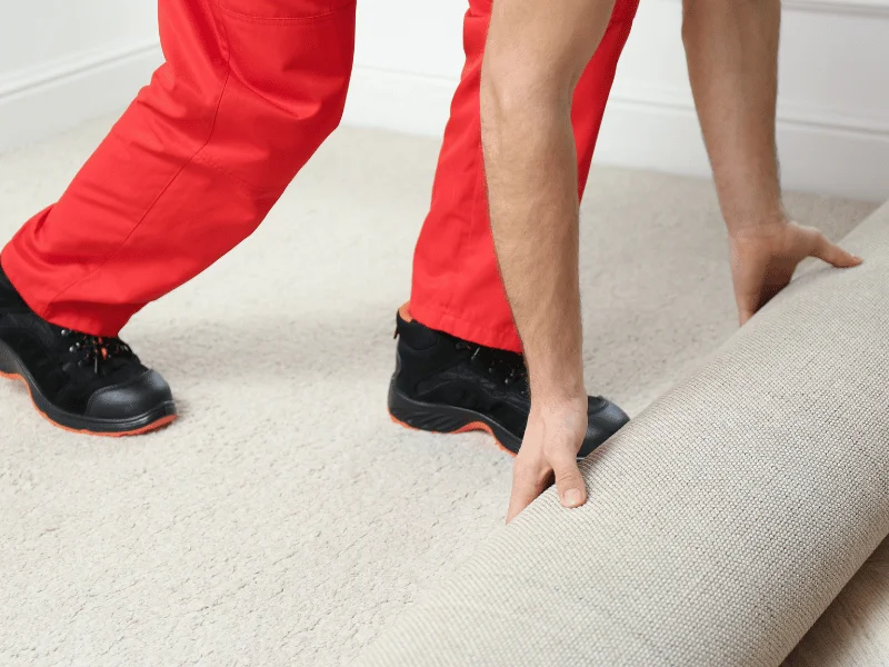 worker unrolls fresh carpeting indoors, closeup